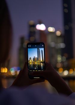 A person photographing Moscow's skyline with a smartphone at night.