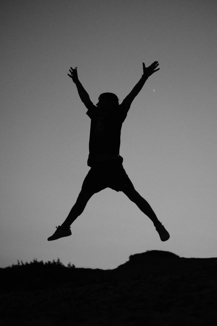 A dynamic silhouette of a person jumping against the twilight sky in İzmir, symbolizing freedom and joy.