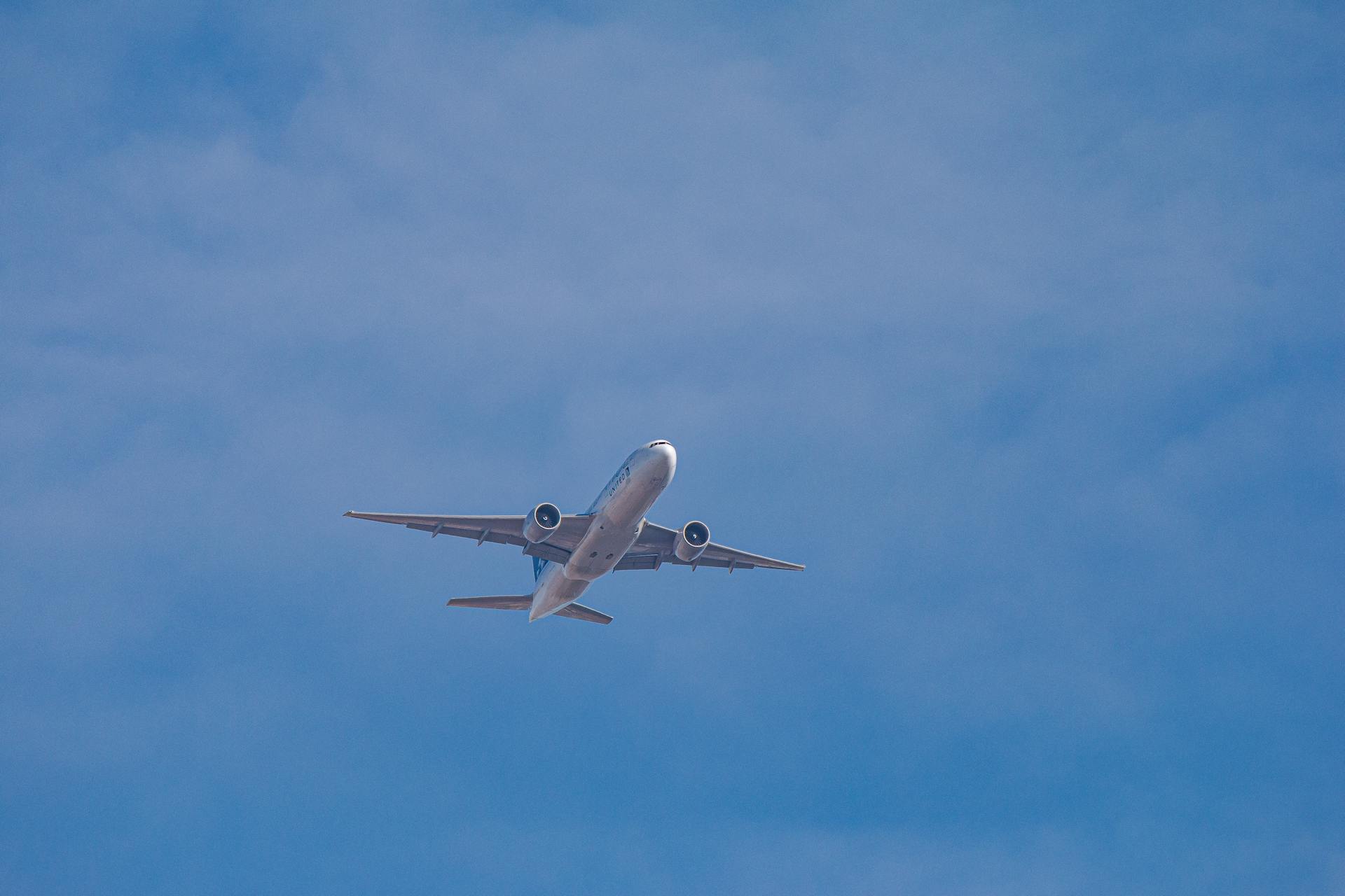 A commercial airliner flying high against a bright blue sky, showcasing modern air travel.