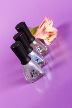 紫色背景上排列着三个指甲油瓶，点缀着粉色花朵