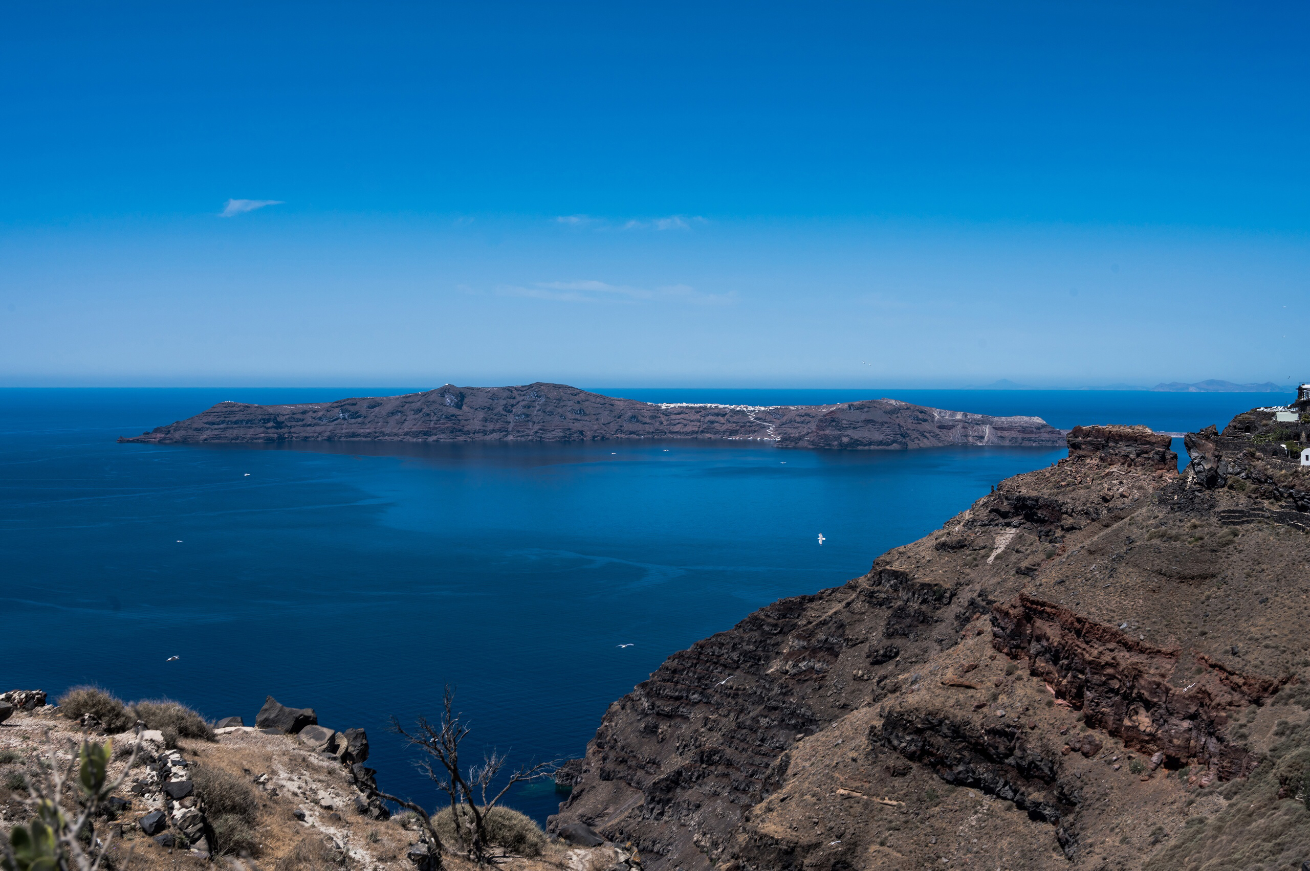 Crystal clear waters at Red Beach Santorini with swimmers enjoying the volcanic beach
