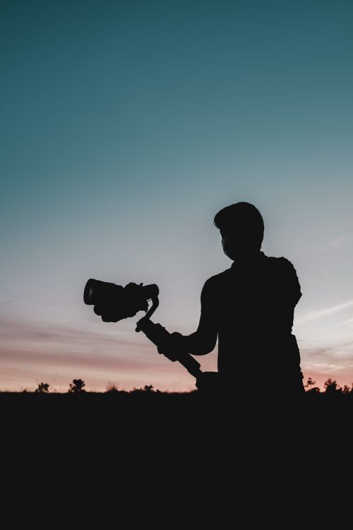 Free Silhouette of a videographer filming during a vibrant Florida sunset, capturing the essence of creativity and nature. Stock Photo