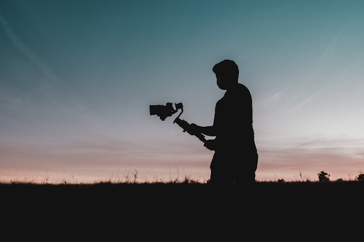 A Silhouette Of Man Holding A Camera