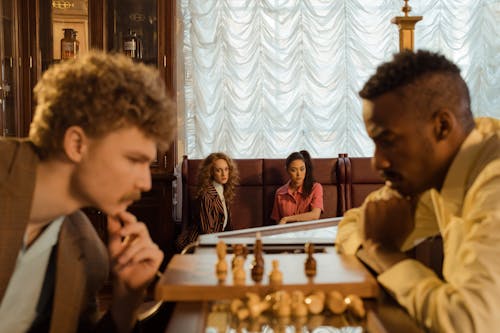 Free A group of diverse adults intensely watching a chess game indoors, depicting focus and strategy. Stock Photo