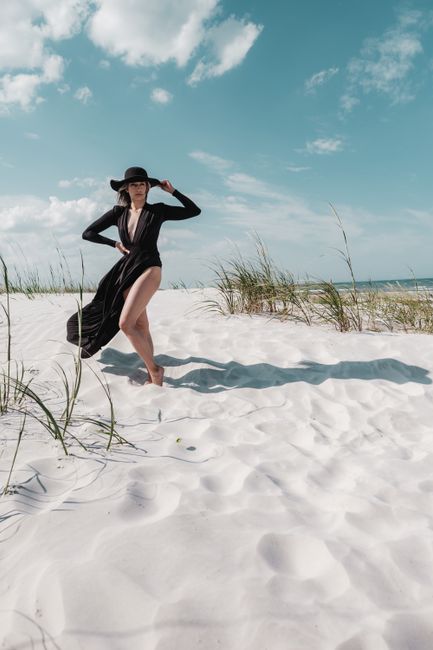Elegant woman in black dress posing on a sunny beach at New Smyrna Beach, FL.