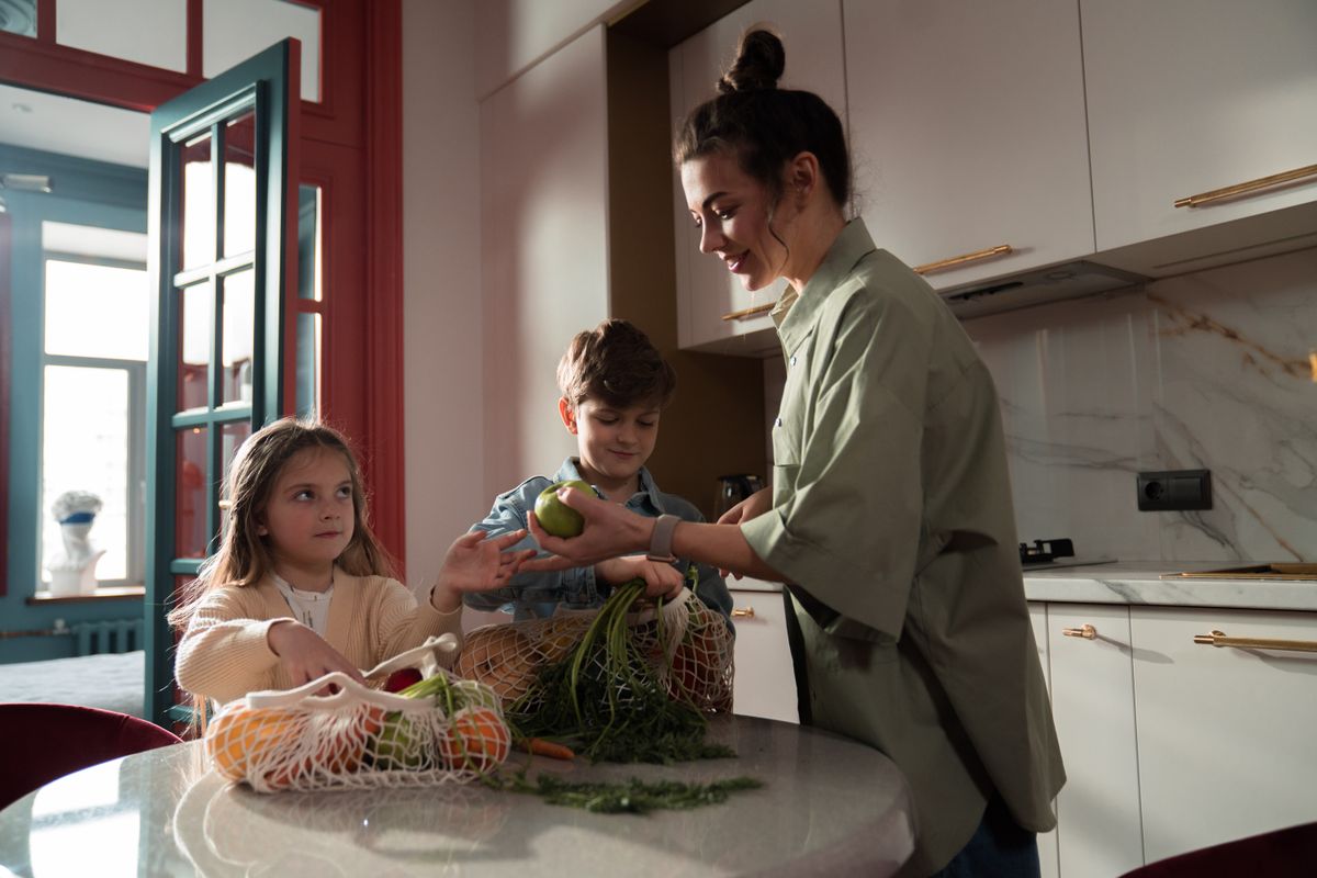 A mother and her children preparing fresh vegetables together in a kitchen