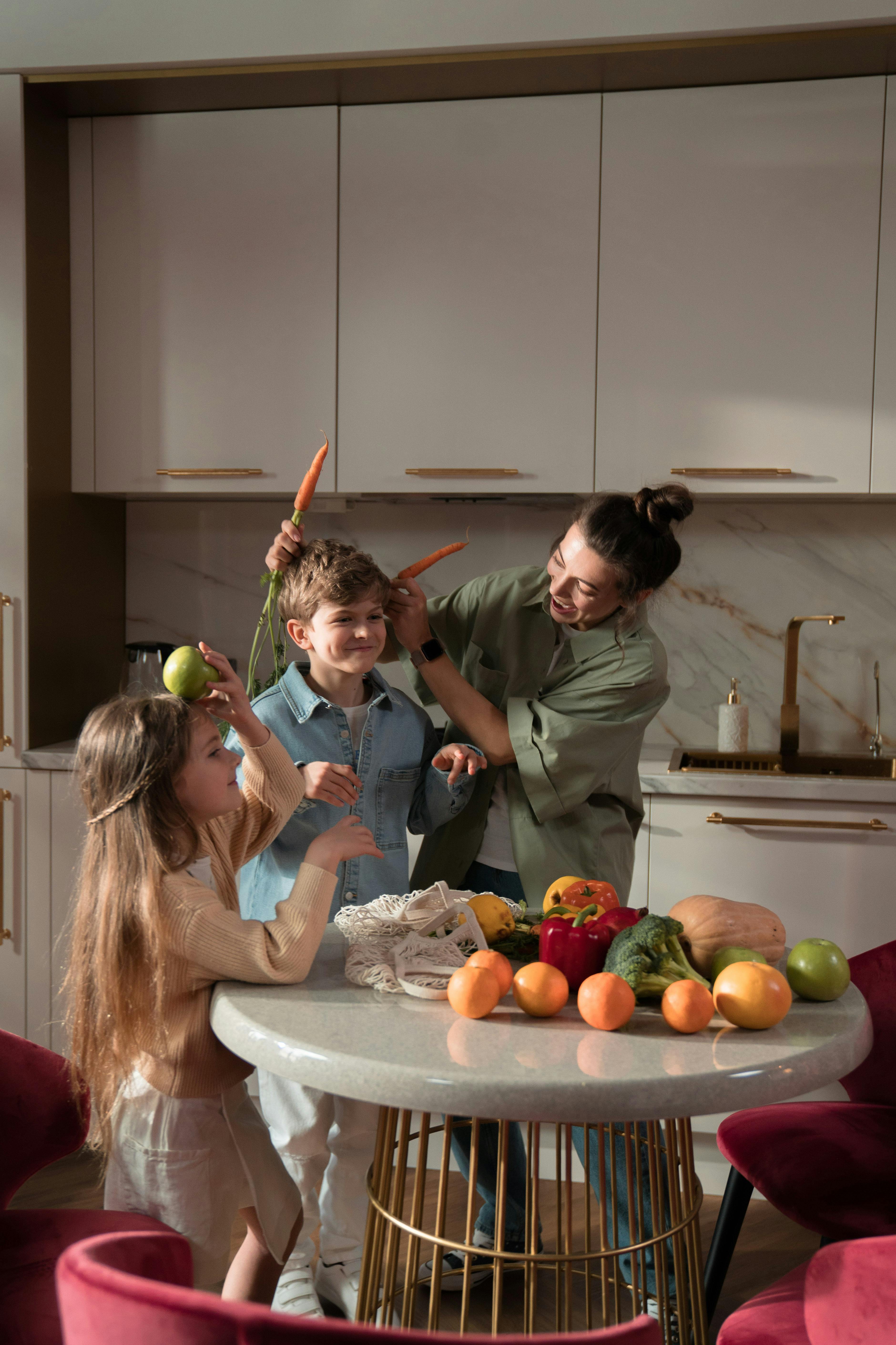 Mother and children having fun with fresh vegetables in a modern kitchen.