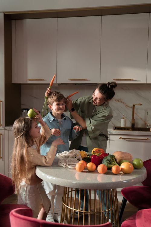 Free Mother and children having fun with fresh vegetables in a modern kitchen. Stock Photo