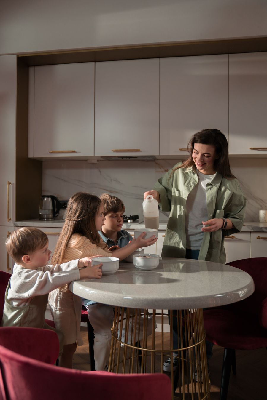 Family at a North London kitchen table; milk being poured into a glass for breakfast