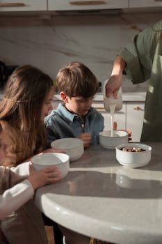 Kids gathered in the kitchen, pouring milk into bowls for breakfast.