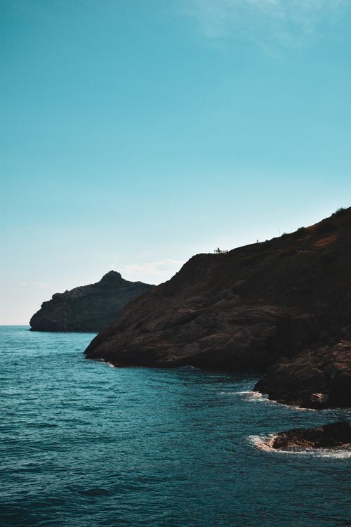 Free Stunning view of rugged coastal cliffs meeting the deep blue sea under a clear blue sky. Stock Photo