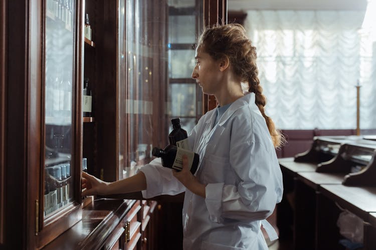 Female Pharmacist Getting Medicines On A Cabinet