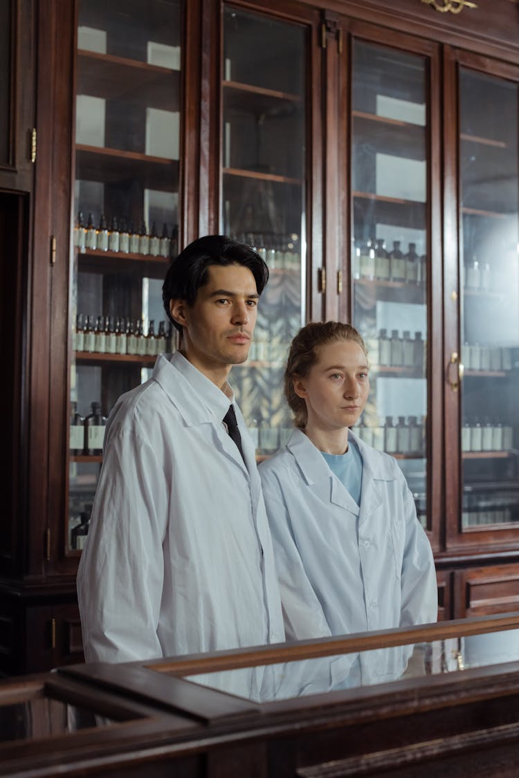 A Man And A Woman Standing Behind The Wooden Counter