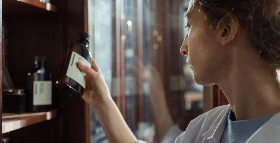 A pharmacist selecting medication — clinic pest control uses low-toxicity, targeted products near medicines and equipment