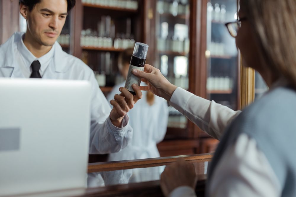 Pharmacist handing medication to a patient across the counter