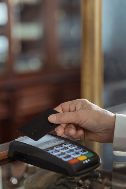 Close-up shot of a hand holding a credit card over a payment terminal in a store. Close-up shot of a hand holding a credit card over a payment terminal in a store.