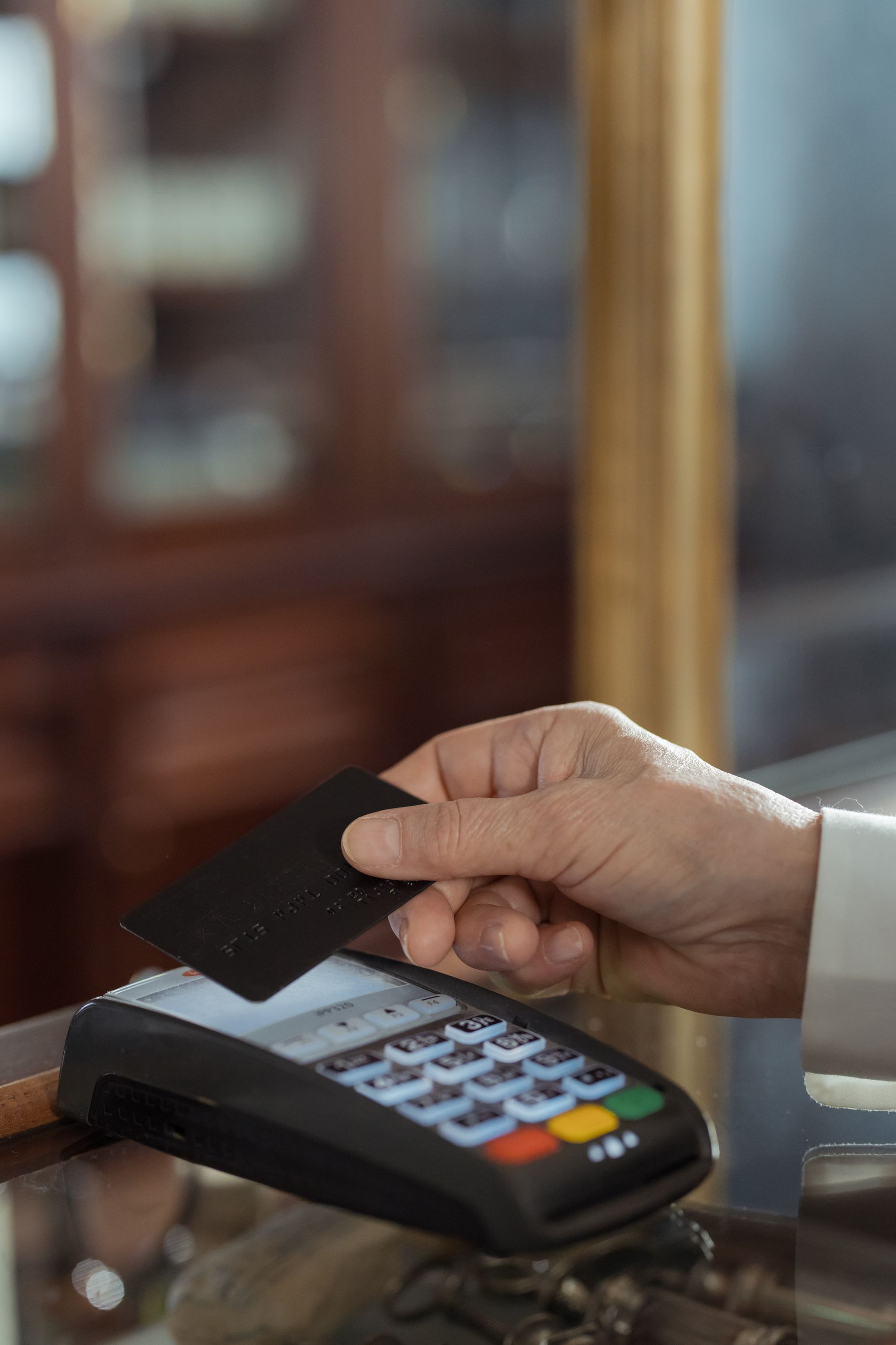 A hand holding a payment card above a card terminal