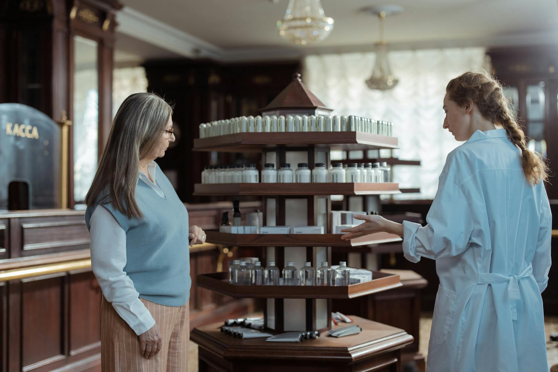 Pharmacist helps customer in elegant pharmacy with rotating product display.