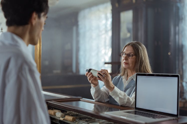 An Elderly Woman With Eyeglasses Looking At A Medicine Bottle