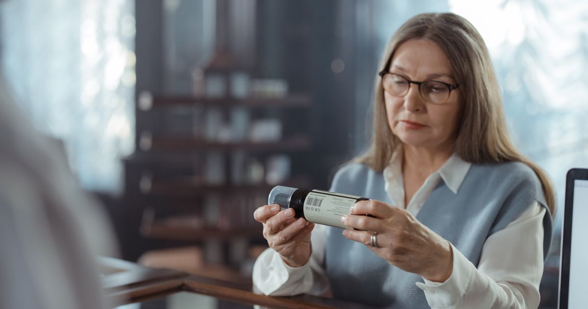 Senior woman with glasses carefully reading the label on a medicine bottle