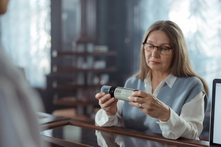 Adult Woman Looking At The Medicine Bottle 