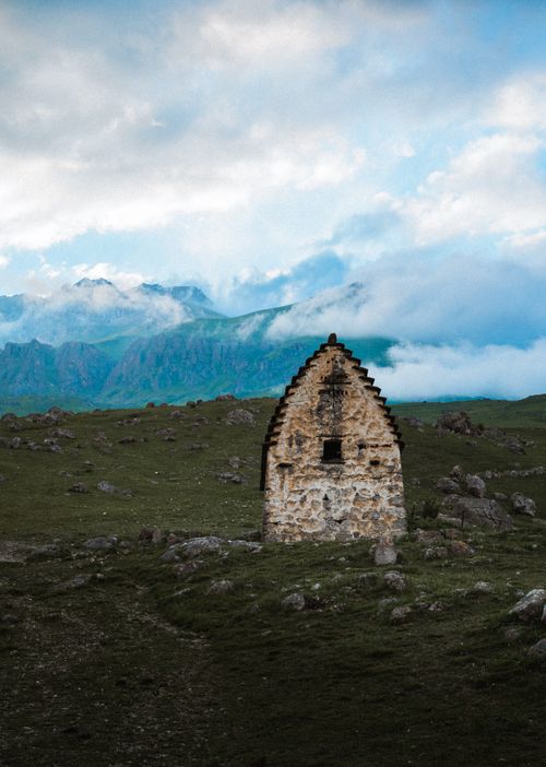 Free Ancient stone building surrounded by rocky hills and clouds in North Ossetia, Russia. Stock Photo