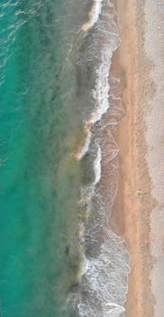 Stunning aerial view of Geremeas Beach, Sardinia with turquoise waves meeting sandy shores.