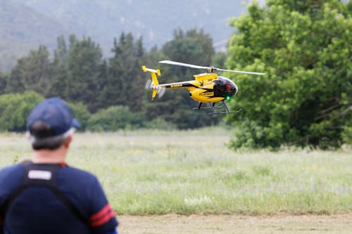 Yellow and Black Helicopter Flying over Green Grass Field