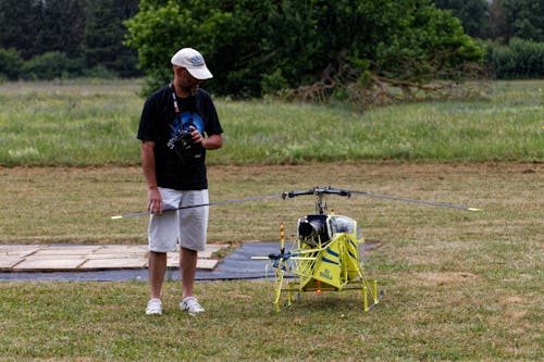 Photo of a Man Standing Beside a Radio-Controlled Helicopter