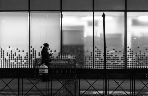 Free Silhouette of a woman walking past a modern building facade. Stock Photo
