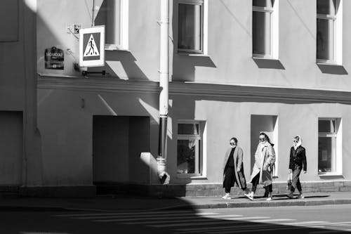 Grayscale Photo of a Man and Women Walking on Sidewalk