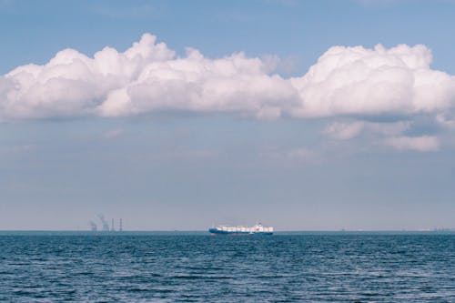 Photo of a Cargo Ship Under White Clouds