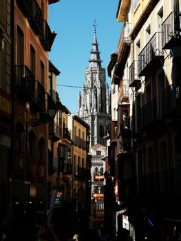 Scenic view of Toledo Cathedral from a narrow alley lined with colorful apartment buildings.