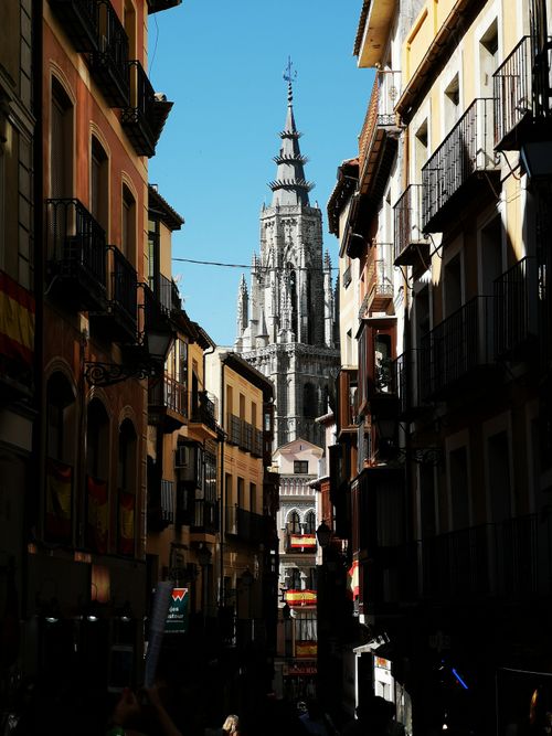 Free Scenic view of Toledo Cathedral from a narrow alley lined with colorful apartment buildings. Stock Photo