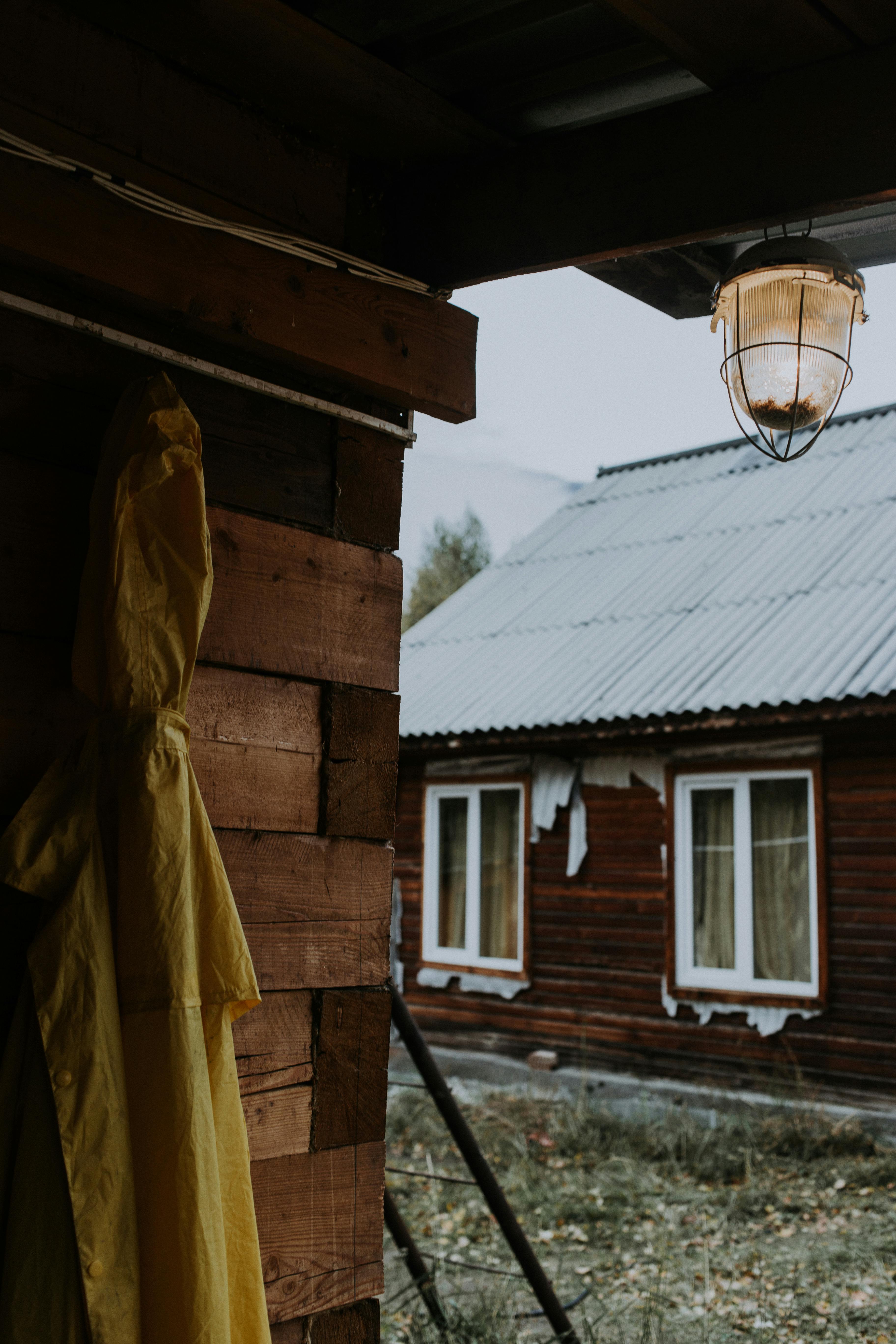 Wooden cabin and yellow raincoat hanging under porch in rural Altai Republic, Russia.