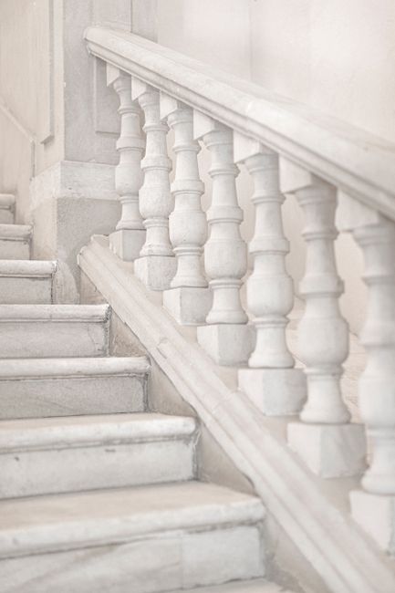 A close-up view of a classic marble staircase with ornate balustrade in soft lighting.
