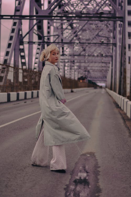 Woman in Gray Coat Standing on Gray Asphalt Road