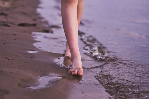 Barefooted Person Walking on the Brown Sand 