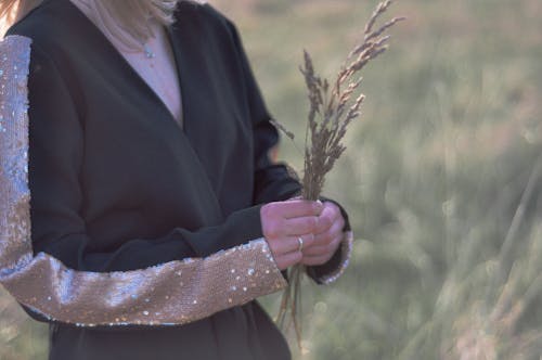 Person in Black Coat Holding a Bunch of Wheat 