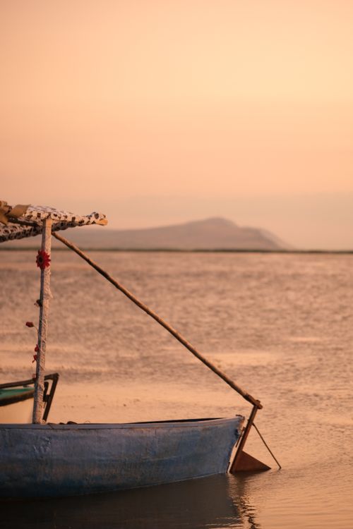 Free A tranquil scene of a wooden boat by the ocean at sunset, with calm waters and soft light. Stock Photo