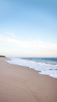 A tranquil beach with gentle waves and a clear blue sky in Kaliningrad Oblast, Russia.