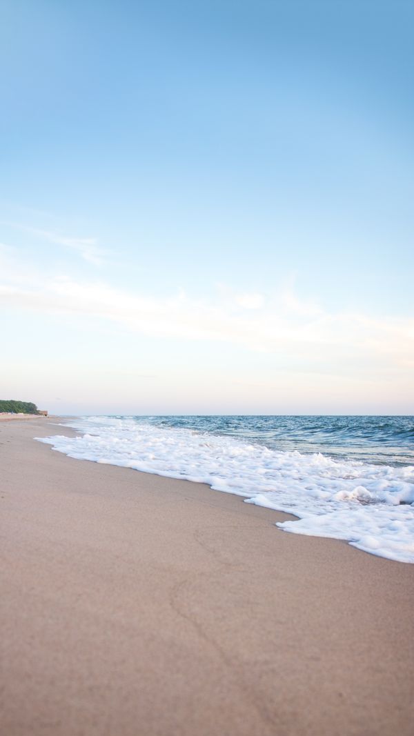 Uma praia tranquila com ondas suaves e um céu azul claro em Kaliningrado, Rússia.