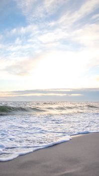 Peaceful ocean waves on the shore under a cloudy sky. Ideal for serene and natural environment themes.