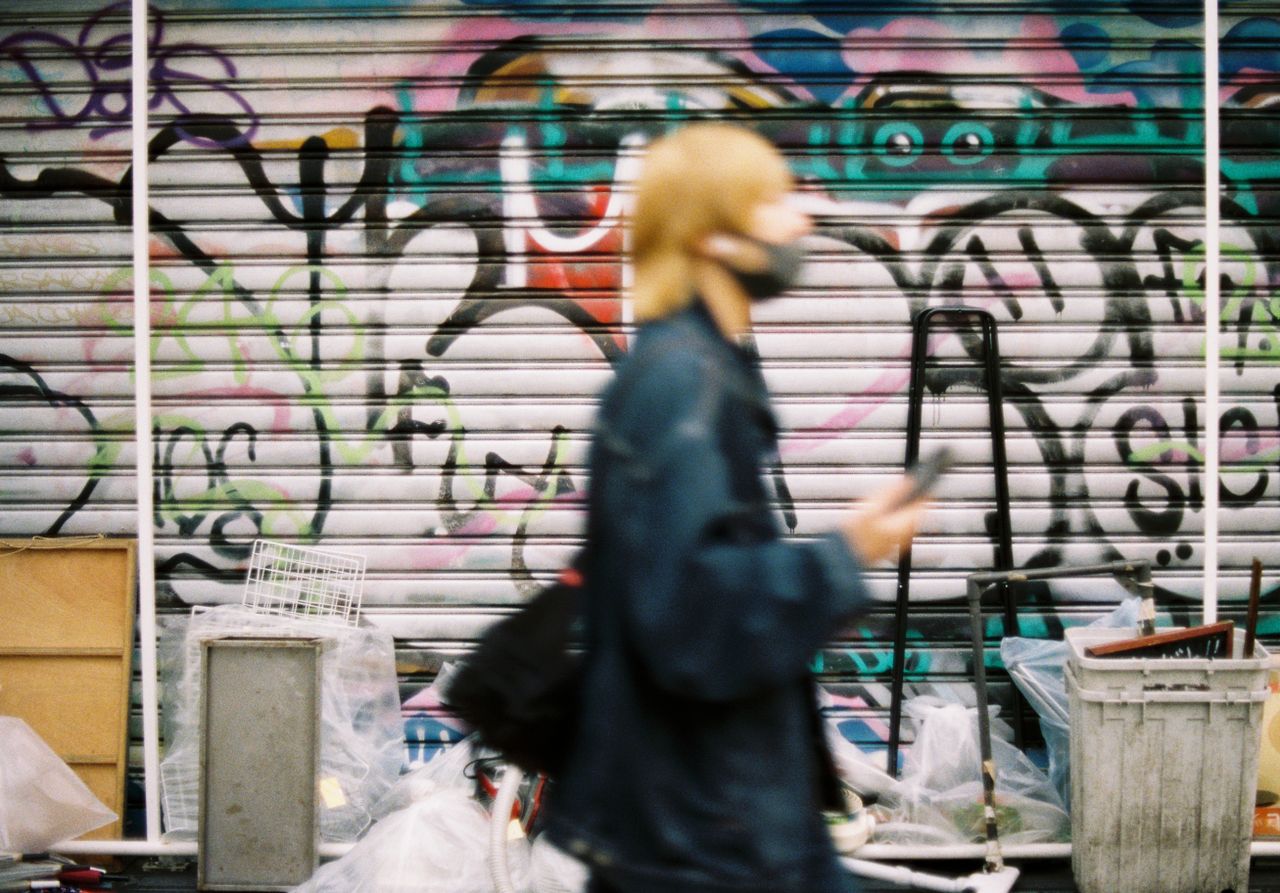 a person passes by a graffiti covered shutter capturing urban life and