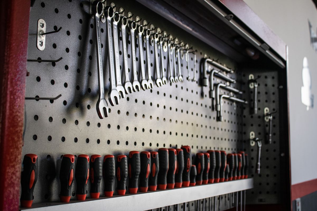 Wrenches, hex keys, and screwdrivers neatly arranged on a garage pegboard for winter organization