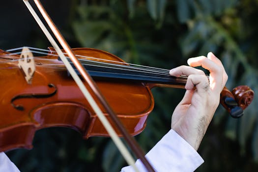 Detailed shot of a musician's hand skillfully playing a violin outdoors with natural lighting.