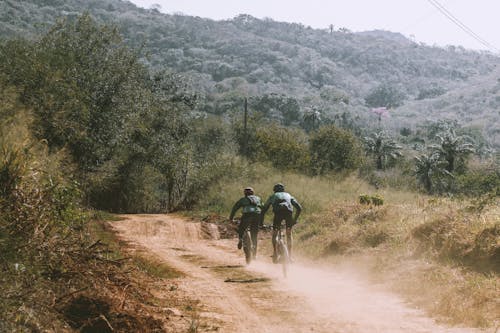 People Riding Bicycles on Unpaved Pathway 