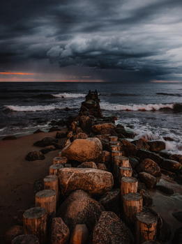 Moody seascape with big rocks leading into the ocean under a stormy sky.