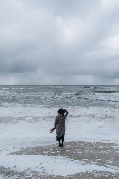 Photo of a Person Standing on a Beach on a Windy Day