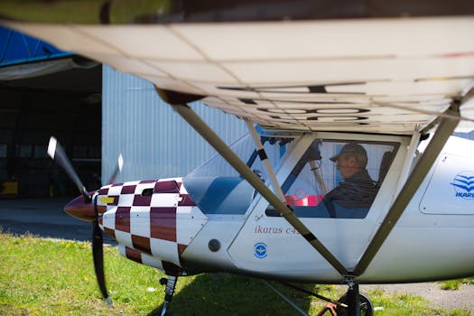 Light aircraft parked near a hangar with a pilot inside ready for takeoff.